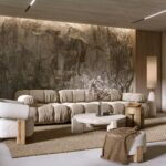 Helles wohnzimmer mit grosser natursteinwand, heller couch und natuerlicher lichtstimmung